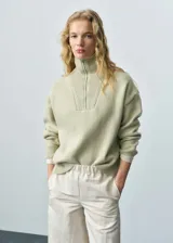 Jersey de punto de lana con cuello alto y cierre de cremallera frontal. Presenta un diseño oversize con mangas largas y terminaciones en canalé.