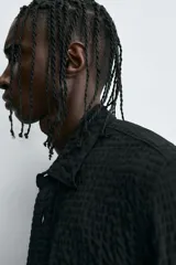 Camisa de hombre de corte relaxed fit, color negro, con textura de cuadros en relieve. Presenta cuello solapa, manga larga con puño abotonado y cierre frontal de botonadura.