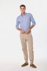 Pantalón de vestir color verde oliva, de corte recto, con bolsillos laterales y traseros. Se ajusta a la cintura con cinturón de cuero marrón.