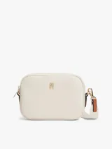 Cartera bandolera rectangular de tejido técnico color beige, con cierre de cremallera, correa tejida ajustable y extraíble, y detalle de monograma TH metálico en la parte delantera.