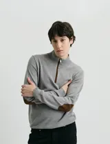 Sweater de punto azul con medio cierre frontal, cuello alto y detalles en símil nappa en la cartera del cierre y coderas.
