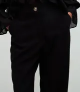 Pantalón de sastrería modelo wide leg, de tiro alto, confeccionado en tejido crepé. Presenta cierre frontal con botón y bolsillos traseros decorativos.