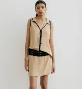 Blusa negra sin mangas con cuello camisero y abertura a los costados, con ribete color beige.