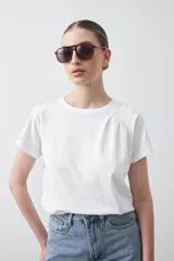 Remera básica de manga corta en color blanco, con cuello redondo y detalle de pliegues sutiles en los hombros.