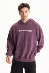 Hoodie y canguro oversize violeta con efecto acid wash, capucha y bolsillo frontal tipo canguro. Presenta un pequeño estampado tipográfico en el pecho con la inscripción 'DAUNTLESS // GOODS & SUCCESS CO'.