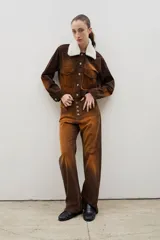 Pantalón de tiro alto confeccionado en pana, con corte recto y cierre frontal de botones visibles. Presenta un diseño con efecto gastado en degradé en tonos marrones y ocres.