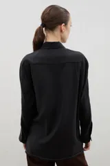 Camisa de corte holgado y diseño clásico, confeccionada en tela satinada con un sutil estampado floral tono sobre tono. Presenta cuello camisero, cierre frontal con botones y mangas largas con puños rectos.