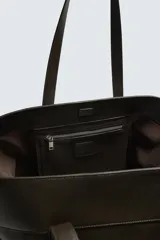 Bolso tipo shopper de piel en color negro, con diseño minimalista, doble asa de mano y compartimento principal con cierre magnético.