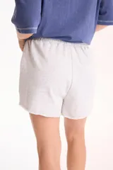 Short deportivo sin friza color beige, con cintura elástica con cordón ajustable, bolsillos laterales y terminaciones deshilachadas.
