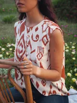 Chaleco de lino estampado con diseño ikat en tonos marrón y crudo, sin mangas, con cuello redondo y cierre frontal de botones tapados.