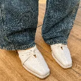 Zueco de cuero vacuno color negro, con diseño de nudo en el empeine y punta cuadrada. Cuenta con un taco bajo de madera y suela de cuero.