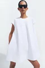Vestido corto Zara de la colección ZW Collection, color beige, confeccionado en mezcla de algodón. Presenta cuello redondo, manga corta, bolsillos laterales ocultos en costura, bajo evasé y cierre en la espalda con cremallera.