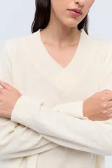 Sweater de tejido de punto color beige, con escote en V y calce holgado.