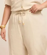 Pantalón de sarga color beige, modelo pantacourt (largo a media pantorrilla) con elástico y amarre en la cintura.