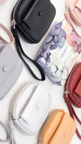 Monedero compacto de símil cuero con textura granulada, cuenta con un compartimento principal con cierre, correa de mano y un bolsillo frontal con solapa y botón a presión.