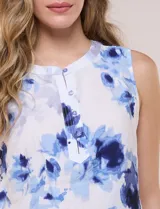 Blusa sin mangas de viscosa blanca con estampado floral en tonos azules, cuello redondo y cierre frontal parcial con botones.