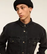 Camisa masculina Blue Steel de corte oversized tipo boxy, confeccionada en denim de algodón con efecto marmolado. Presenta cuello camisero, mangas largas, cierre frontal con botones metálicos y dos bolsillos con solapa en el pecho.