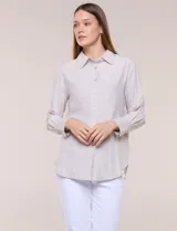Camisa de calce relajado color celeste, confeccionada en tejido de textura suave y fluida. Presenta cuello camisero y abotonadura frontal, mangas largas con puño ancho y ruedo curvo.