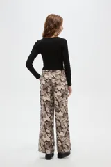 Pantalon de corte baggy con cintura media y bolsillos laterales. Presenta un estampado abstracto tipo camuflado en tonos tierra.