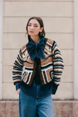 Saco tejido en crochet con diseño de rayas horizontales en mangas y espalda. Presenta un cierre frontal con lazos de crochet en el escote en V y detalle de flecos en el ruedo.