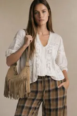 Blusa de color crudo con diseño oversize, confeccionada en una mezcla de viscosa y lino. Presenta detalles de encaje vertical en el frente y en las mangas, escote en V y mangas tres cuartos con terminación elástica.