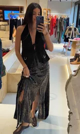 Chaleco top negro de cuero con escote halter profundo, cierre frontal con lazos regulables y bolsillos aplicados al frente con detalles metálicos.