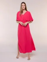 Vestido largo amarillo de corte fluido con escote en V, mangas cortas amplias y apliques de tachas en el escote y puños. Posee cintura elastizada fruncida y falda larga con tajos laterales en el ruedo.