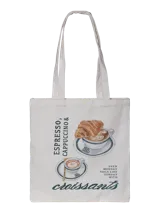 Bolso tipo tote bag color crudo, con estampado frontal ilustrado de tazas de café y croissants, acompañado de inscripciones en tipografía cursiva y de imprenta. Cuenta con dos asas superiores de hombro.