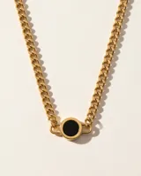 Collar de cadena tipo eslabones gruesos con baño de oro, que presenta un dije central circular con incrustación de piedra ónix negra.