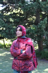 Balaclava tejida con diseño de capucha integrada y bufanda larga, confeccionada en una mezcla de algodón y acrílico con motivos geométricos en tonos rojo y azul.