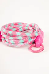 Correa para celular con diseño geométrico en tonos rosa y celeste, con aplique de plástico rosa. Incluye parche de tela rosa para sujetar al celular.