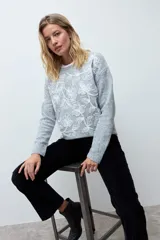 Sweater de punto color rojo con cuello redondo, mangas largas y bordado floral en tono rosado en la parte frontal.