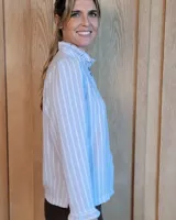 Camisa de manga larga con estampado de rayas verticales en tonos crudo y beige. Presenta cuello alto con volados, cierre frontal con botones dobles y puños con volados.