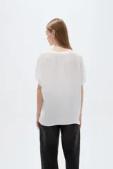Blusa blanca de poliéster de corte holgado, con escote en V y mangas cortas.