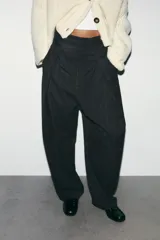 Pantalón de tiro alto con diseño tipo balloon, confeccionado en tejido con estampado de rayas verticales. Presenta pliegues frontales, bolsillos laterales ocultos y cierre frontal con cremallera, botón interior y ganchos metálicos.