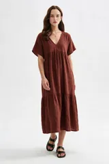 Vestido midi marrón de corte holgado, con escote en V, mangas cortas y detalle de volados fruncidos en el pecho y en el ruedo.
