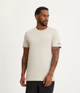 Remera deportiva de hombre con tecnología dry fit, cuello redondo y manga corta. Presenta un diseño minimalista en color beige con una pequeña etiqueta aplicada en el dobladillo y detalles discretos en las mangas.