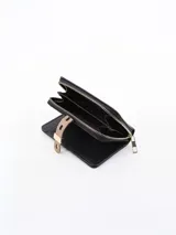 Billetera negra con cierre de cremallera y detalle de hebilla decorativa en color beige.