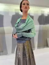 Buzo de doble tejido fino y suave 100% lana merino teñida artesanalmente. Cuenta con una pieza incorporada que permite enroscarla en el cuello a modo de bufanda o chall, dejarla libre hacia el frente o espalda, o enroscarla en el delantero de modo asimétrico. Los puños tienen un ojal para colocar el pulgar y oficiar de semi guantes. Prenda abrigada y confortable ideal para ser usada debajo de un cardigan. Creado y producido en Uruguay.