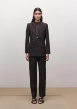 Blazer cruzado de doble botonadura, color marrón oscuro, con solapas de muesca, bolsillos con solapa y hombreras estructuradas.
