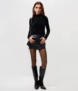 Blusa cropped de punto chenille color negro, con cuello alto y mangas largas raglán. Presenta una textura acanalada y pequeños puntos brillantes aplicados en el frente.