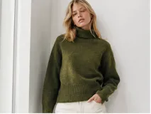 Sweater de cuello alto en color verde musgo, con diseño de tejido de punto suave, corte relajado y terminaciones acanaladas en cuello, puños y cintura.