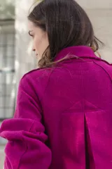 Chaqueta de lana afieltrada color amarillo, con cuello camisero, cierre frontal con broches a presión y bolsillos delanteros. Presenta un diseño de corte holgado con una apertura en la espalda que aporta movimiento.