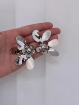 Aros colgantes con diseño de flor metálica plateada de pétalos grandes y brillantes.