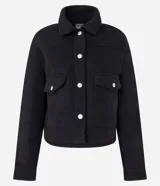 Campera corta negra de polivelour con cuello inglés, manga larga, cierre abotonado, bolsillos con solapa y botones en el pecho.