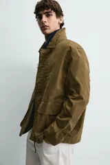 Parka de corte relajado confeccionada en mezcla de algodón color marrón. Presenta cuello solapa, cierre frontal con cremallera oculta y alamares metálicos, bolsillos de plastrón con solapa en la cadera y bolsillo de vivo en el pecho.