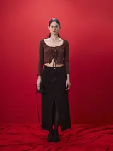 Falda larga de denim negro con corte recto, tiro medio y tajo frontal central. Presenta costuras a la vista en tono contrastante y cierre frontal con botón metálico.