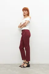 Pantalón de vestir color bordó, de corte recto, con bolsillos laterales y traseros. Se ajusta a la cintura con cinturón de cuero marrón.