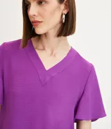 Blusa color violeta con cuello en V, mangas cortas con volados y textura airflow.