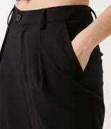 Pantalón negro de corte wide leg, estilo sastrero, con pliegues frontales y cierre con botón.